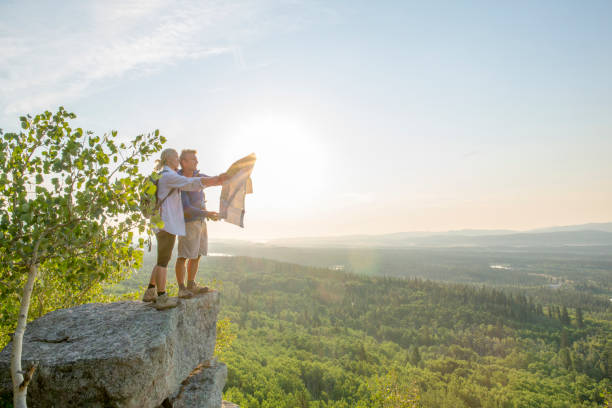 couples de randonnée regardent la carte sur le sommet de roche - rock climbing mountain climbing women achievement photos et images de collection