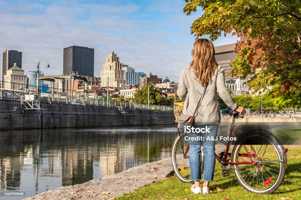 Bike ride in Montreal. Portuguese woman doing a bike ride in Montreal Old Port and looking at the downtown district during a sunrise in the end of summer. Montréal Stock Photo