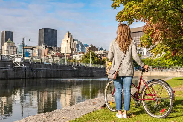 Portuguese woman doing a bike ride in Montreal Old Port and looking at the downtown district during a sunrise in the end of summer.