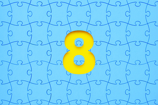 Blue jigsaw puzzle pieces forming a cut out number eight on yellow background. Horizontal composition with copy space. Solution concept.