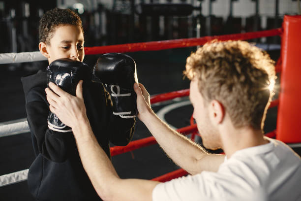 istock Little boy in boxing gloves on ring with trainer 1303755798