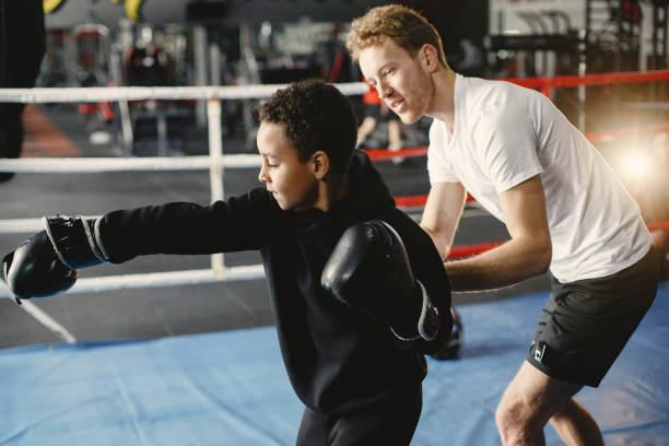istock Little boy in boxing gloves on ring with trainer 1303755809