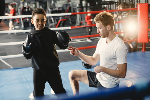 istock Little boy in boxing gloves on ring with trainer 1303755810