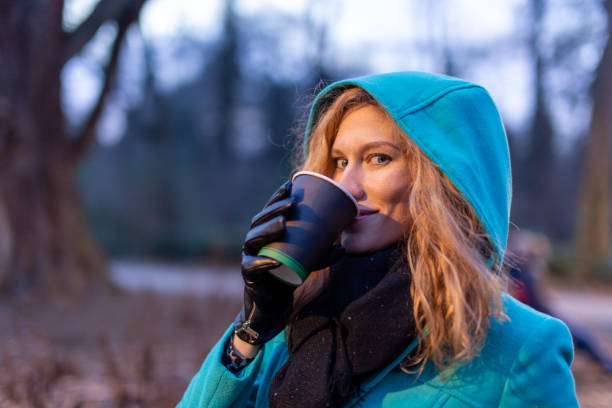 Sensual young redhead Caucasian woman drink hot refreshment, outdoors, evening or night