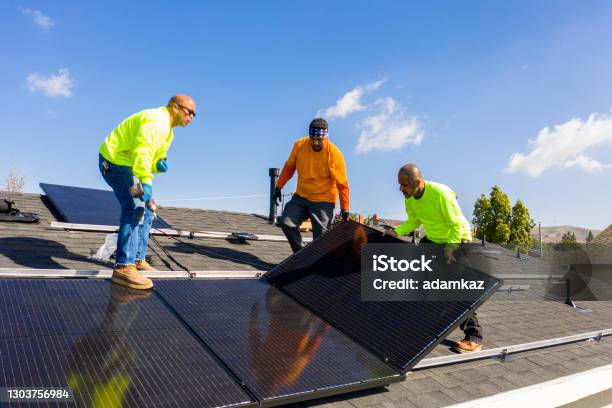 Team Of Workers Installing Solar Panels On Residential Rooftop In California Stock Photo - Download Image Now
