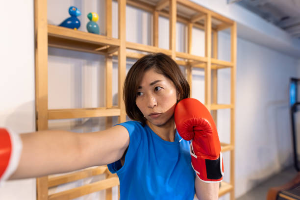 Japanese woman with red boxing glove boxercising in gym Sports athletes exercising in gym and doing yoga on the rooftop of the building. boxercise stock pictures, royalty-free photos & images