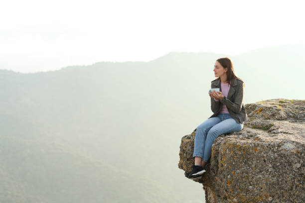 istock Woman drinking coffee contemplating views from cliff 1303761309