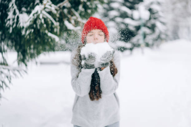 istock The girl blows snow from her hands. Winter forest 1303762731
