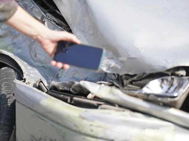 istock hand take photo of crashed damaged broken car. automobile crash accident 1303762939