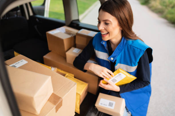 istock Smiling young delivery woman loading the trunk with packages and mail for delivery 1303770315