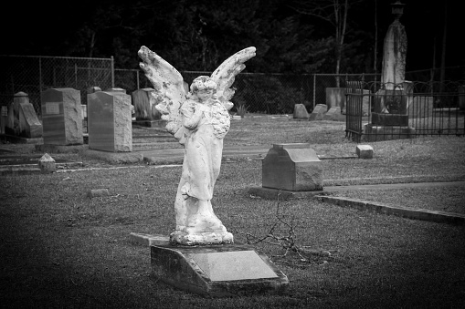 no name spooky grave headstone angel statue in a creepy old cemetery in black and white
