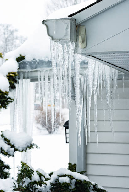 istock Multiple Heavy Frozen Winter Icicles Hanging From Roof Gutter 1303774238