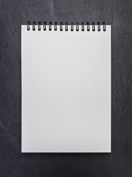 istock Empty blank page of notepad on black slate background. Mockup. Flat lay 1303774270