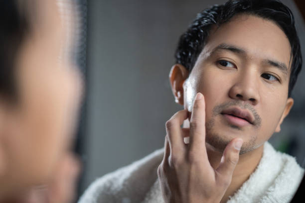 istock Asian man looking in the mirror at bathroom He touch his face 1303774342
