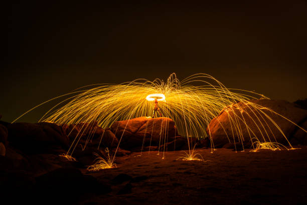 istock Fire dancing show swing lighting effects circle on bridge dark sky on night time. 1303775903