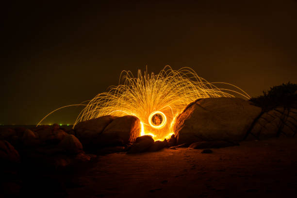 istock Fire dancing show swing lighting effects circle on bridge dark sky on night time. 1303775954
