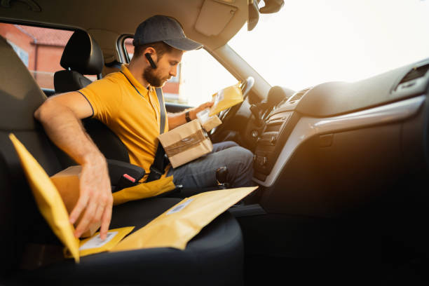 istock Young courier looking at the packages and mail for delivering 1303777864