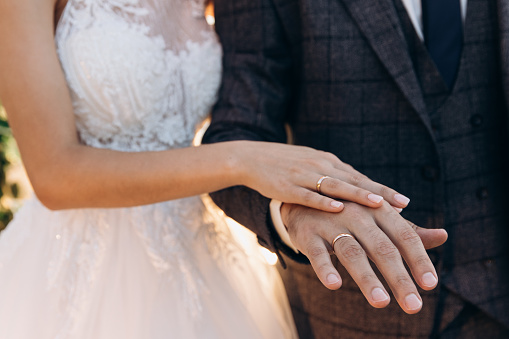 The graceful hand of a woman lies on a man's hand. People have gold wedding rings on their hands. High quality photo