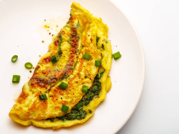 istock Omelet with spinach, green onions and cherry tomato on a white plate. 1303780759