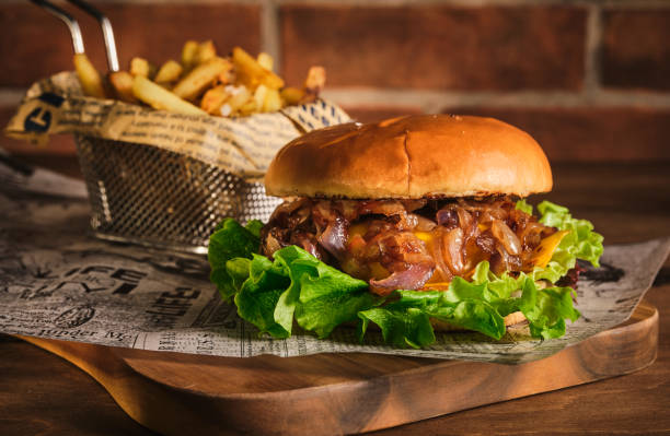 istock Burger with beef and caramelized onions on a wooden board. Cheeseburger with onion and beef. Juicy Delicious Homemade Burger. 1303780874
