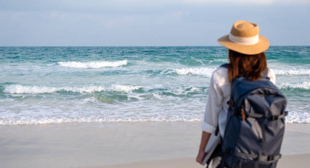 istock a female traveler holding laptop computer while walking on the beach 1303783318