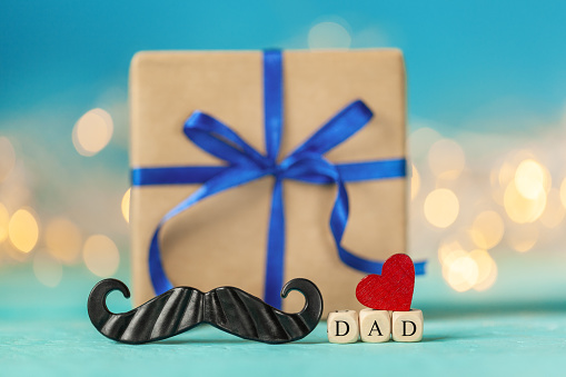 Happy Father s Day greeting card with gift box and red heart on blue background.