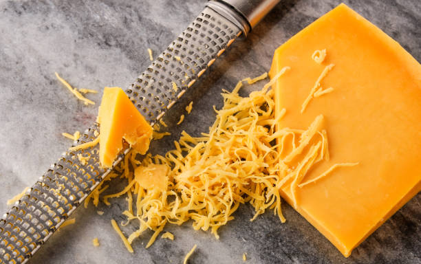 istock Grated Gouda cheese and a grater on a stone table. 1303786077