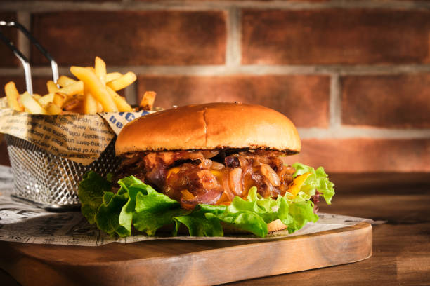 istock Burger with beef and caramelized onions on a wooden board. Cheeseburger with onion and beef. Juicy Delicious Homemade Burger. 1303787074