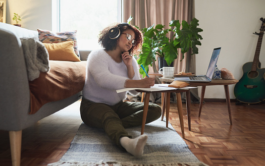 Shot of a young woman wearing headphones while working at home