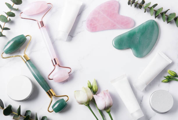 istock Cosmetic products cream tubes,  face roller and eucalyptus  on marble background. 1303790815