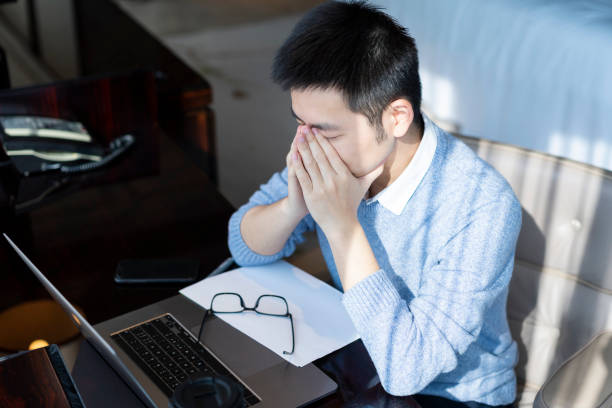 istock Asian man getting tired and doing eye exercises while working at home 1303791755