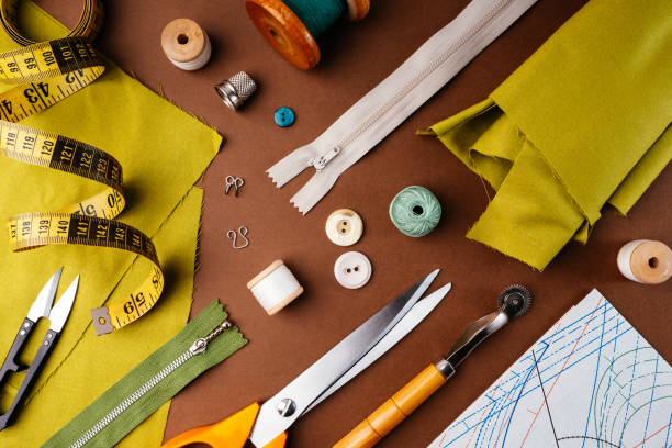 istock Flat lay composition of sewing accessories, scissors, patterns, fabrics on a brown background, top view. The desktop of a fashion designer, tailor in an atelier. Vintage style sewing concept 1303792769