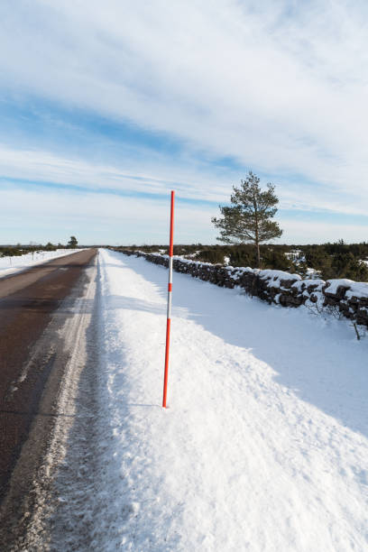 istock Country road with a red snow stake by roadside 1303793646