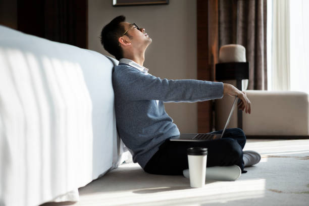 istock Asian man getting tired while working at bedroom with laptop and mobile phone 1303794008