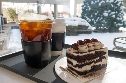 Two refreshing coffees with chocolate cake on the table with bright sunshine
