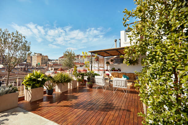Rooftop Deck of Modern Barcelona Apartment Spacious outdoor deck with hardwood floor, covered seating area, potted plants and a sun-filled view of the city. balcony stock pictures, royalty-free photos & images