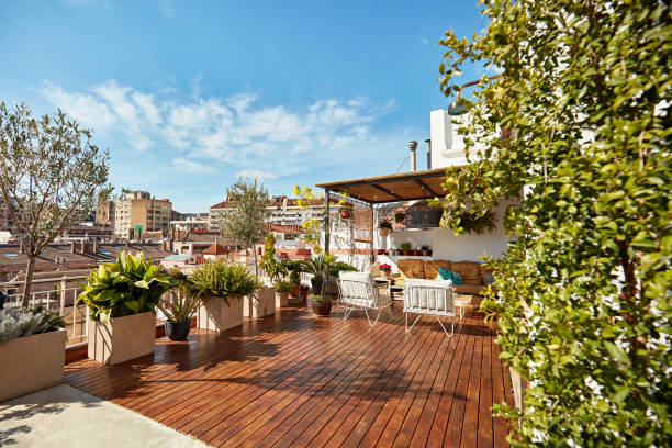 Rooftop Deck of Modern Barcelona Apartment Spacious outdoor deck with hardwood floor, covered seating area, potted plants and a sun-filled view of the city. apartment balcony garden stock pictures, royalty-free photos & images