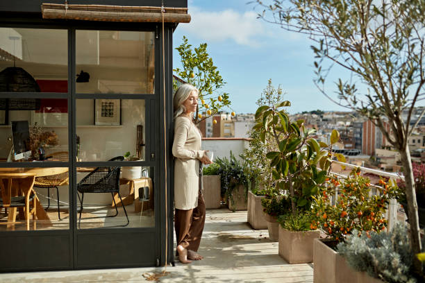 istock Relaxed Senior Woman Standing on Sunny Deck with Coffee 1303798215