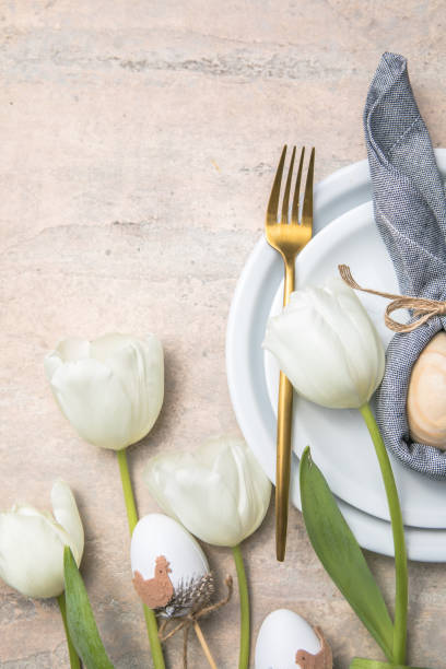 istock Easter holiday table setting with bunny  from egg on white plate and tulips flowers.  Gray concrete table, top view with copy space for text. Happy Easter background 1303804038