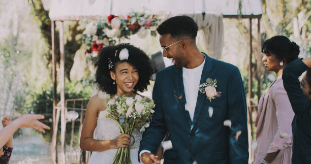 Here's to the beginning of our happily ever after Cropped shot of a newlywed couple walking down the isle together after being announced as husband and wife newlywed stock pictures, royalty-free photos & images