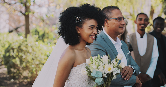 Father walking daughter bride down the aisle for LGBTQ+ wedding. This is part of a series about a lesbian couple getting married. Horizontal outdoors waist up shot with copy space.