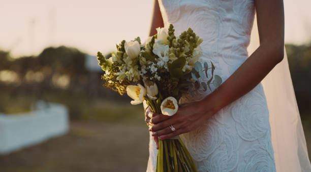 Love lives in the smallest of details Cropped shot of an unrecognizable bride standing alone outside and holding her bouquet on her wedding day wedding dresses stock pictures, royalty-free photos & images