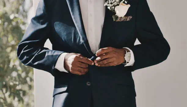 Cropped shot of an unrecognizable groom standing alone and getting ready before his wedding