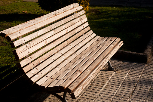 An old faded wooden park bench in the sun.