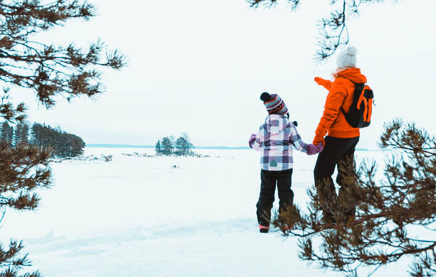 familie von kaukasiern, die im winterwald spazieren gehen. junge frau mit einem kind 5 jahre alt. - child winter snow 4 5 years stock-fotos und bilder