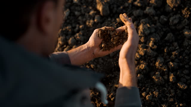 SLO MO Farmer examining soil on a field