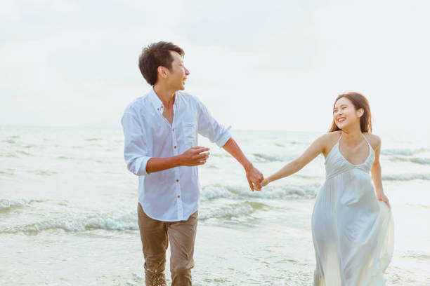 istock Young couple holding hands and running on the beach. 1303806527