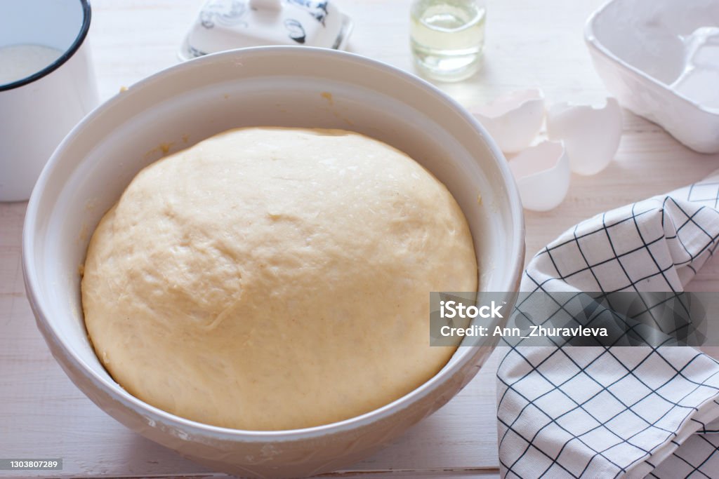 Freshly cooked yeast dough in ceramic bowl on white wooden table, selective focus Proofing - Baking Technique Stock Photo