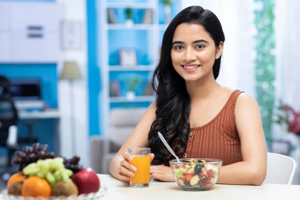 young women drinking orange juice and eating  fruit salad  stock photo adult , adult only, young women , India, Indian ethnicity, healthy indian food stock pictures, royalty-free photos & images