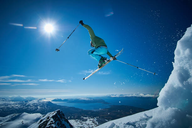 Skier jumping in a mountain and fjord landscape. Single skier jumping high above a Northern Norway fjord and island landscape. extreme sports stock pictures, royalty-free photos & images